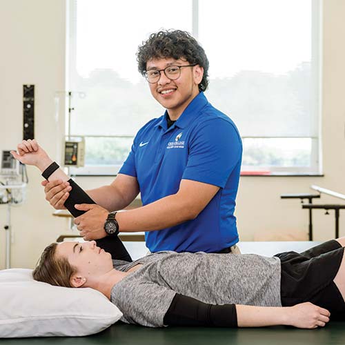 Cecil College male physical therapist assistant student providing therapy to female PTA student on therapy table