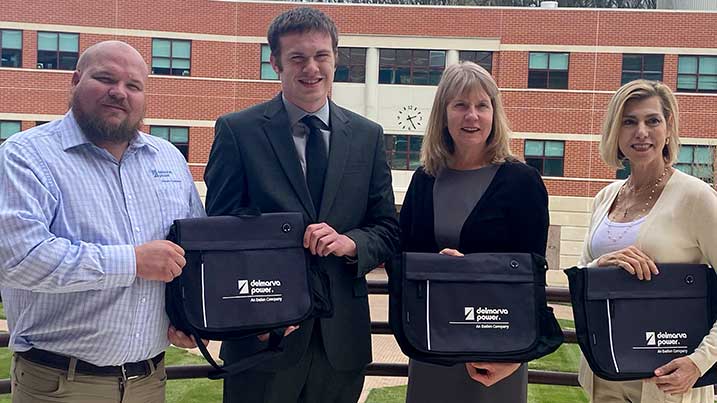 This is a photo of Seen here are Jeffrey Emmons, Senior Public Affairs Manager at Delmarva Power; Michael Moore, Director of IT Client Services at Cecil College; Dr. Mary Way Bolt, Cecil College President; and Karen Uricoli, Executive Director of the Cecil College Foundation holding up the computer bags.