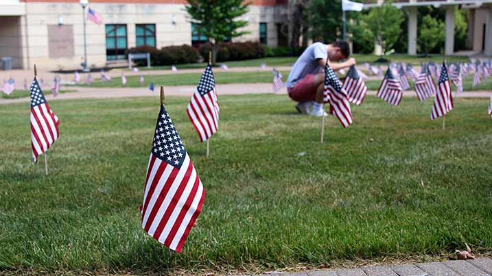 A Cecil College student kneels to plant a flag in the quad of the North East Campus.