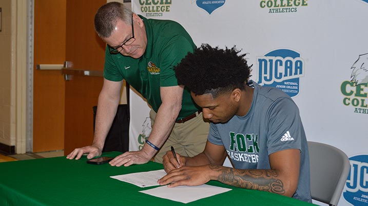 Cecil College head men's basketball coach Ed Durham looks on as the Seahawks' star player, Khalid Gates, signs his Letter of Intent to transfer to play for Slippery Rock University.