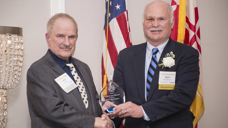 John Casner, executive director of Northeastern Maryland Technology Council (NMTC) presenting the Leader Award to Mark Mortenson, co-founder and Chief Technology Officer at Clene Nanomedicine during the Ninth Annual Visionary Awards Ceremony on Thursday, Feb. 27. The Leader Award acknowledges an individual’s steadfast, consistent contribution to the building Maryland’s STEM-educated workforce or advancing technology and innovation in a public way while inspiring others to help in accomplishing shared goals.