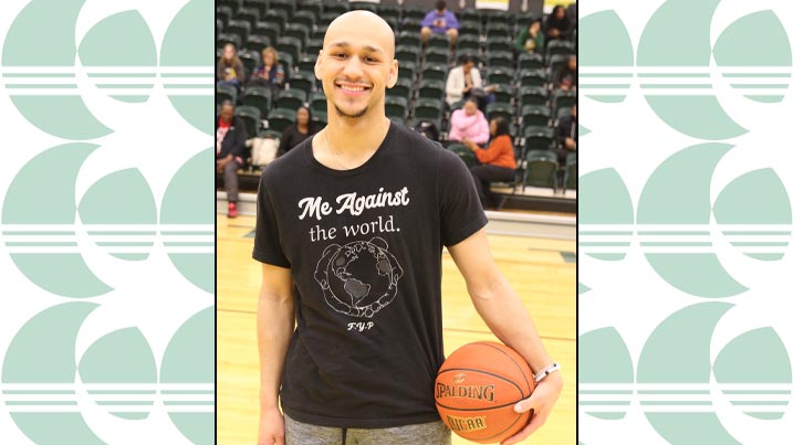 McKale Williams displays one of his designs on his shirt during the 2024 Cecil College Alumni Basketball Game. He is holding a basketball under his arm in the photograph.