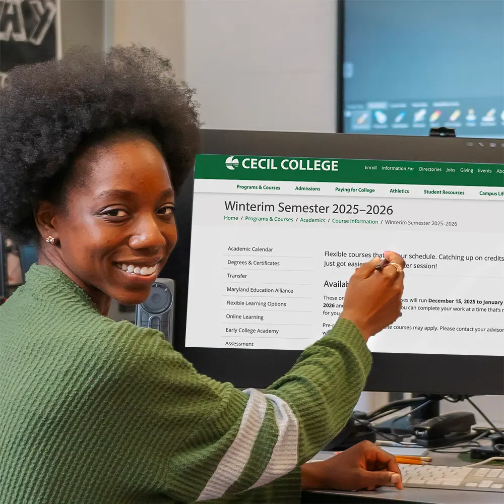 Cecil College student pointing to computer screen in visual communications lab