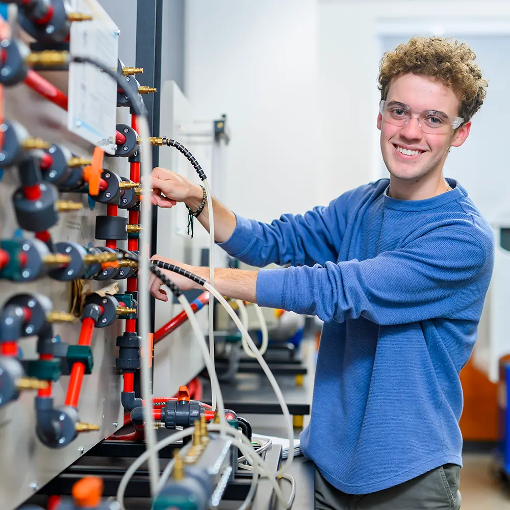 male engineering student at control board smiling at camera for cecil college enroll for spring campaign