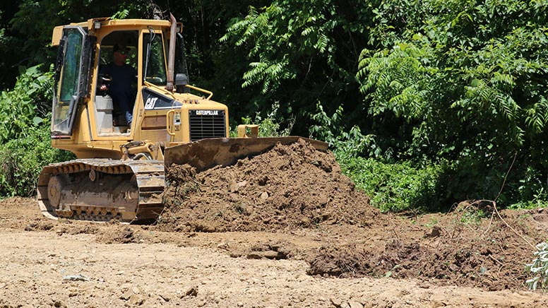 A bulldozer moving dirt for the new athletic building