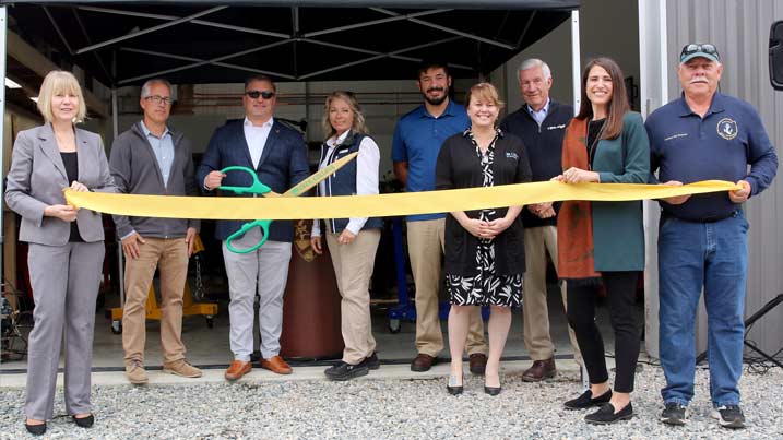 College, industry, and county officials holding a ribbon during a ribbon cutting ceremony.