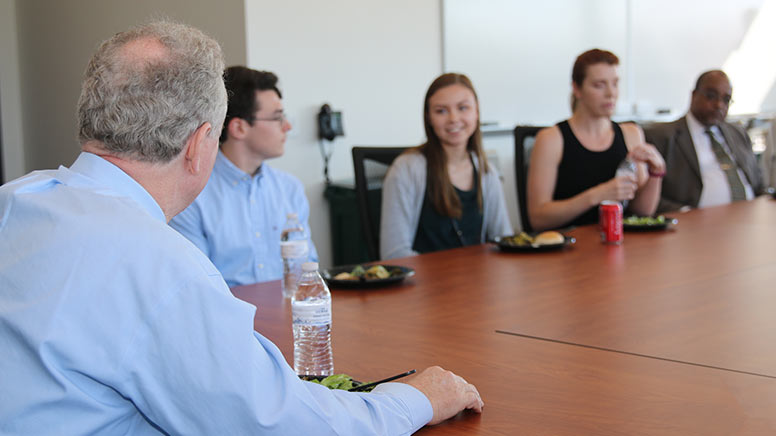 U.S. Sen. Chris Van Hollen sitting with cybersecurity faculty and students.