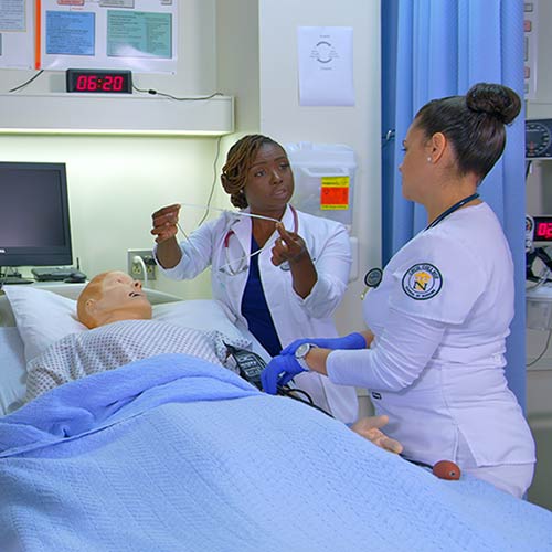 Nursing Instructor at Cecil College instructing student over hospital bed