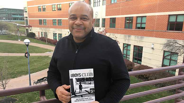 Dr. Beckles holding his latest book.