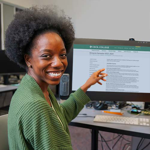 Cecil College student pointing to computer screen in visual communications lab