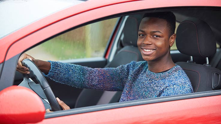 Teenager driving a red car.