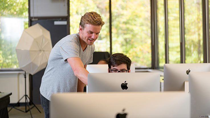 An instructor helping a student at a computer.