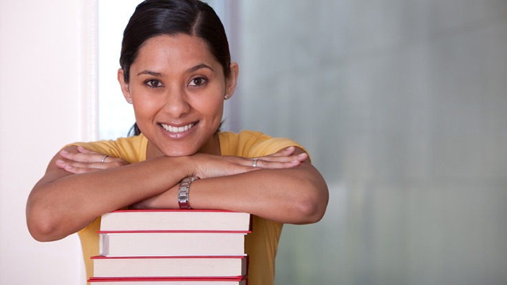 Student leaning on stack of books.