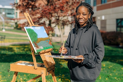 An art student painting outside.