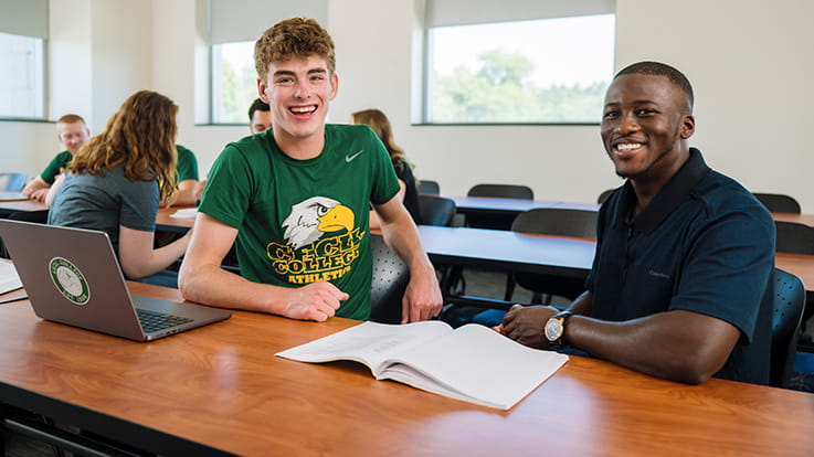 Two students at a desk in a classroom.