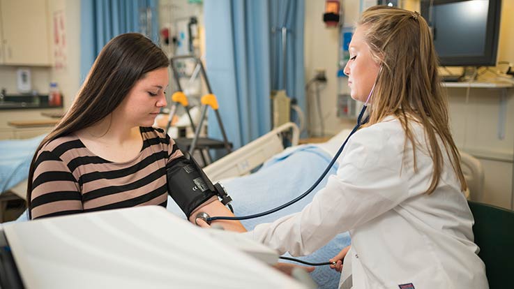 A student taking a patient's blood pressure.